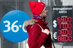 A woman walks past an exchange office screen showing the exchange rates of U.S. Dollar and euro to Russian ruble in Moscow on March 9.