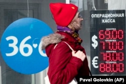 A woman walks past an exchange office screen showing the exchange rates of U.S. Dollar and euro to Russian ruble in Moscow on March 9.