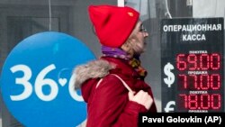 RUSSIA -- A woman walks past an exchange office screen showing the currency exchange rates of U.S. Dollar and Euro to Russian Ruble in Moscow, March 9, 2020