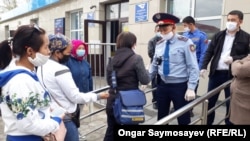 Люди в защитных масках стоят в очереди у почтвого отделения. Кызылорда, 13 апреля 2020 года.