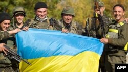 Українські військовослужбовці з прапором на контрольно-пропускному пункті поблизу міста Попасна в Луганській області, 2 жовтня 2014 року