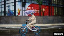 یک زن دوچرخه‌سوار در ووهان در مرکز چین، کانون اولیه شیوع کرونا، در نخستین روز لغو قرنطینه
