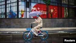 یک زن دوچرخه‌سوار در ووهان چین که گفته می‌شود کانون اولیه شیوع کرونا بوده است.
