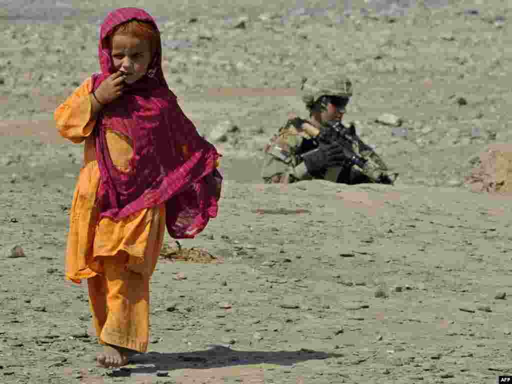 A U.S. Army soldier patrols as a girl walks past in Turkham Nangarhar, bordering Pakistan. (Photo by Tauseef Mustafa for AFP)