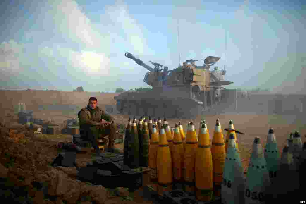 Israeli soldiers rest next to shells from an artillery unit near the Israeli border with Gaza. (epa/Abir Sultan)