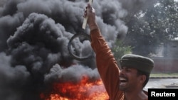 A man shouts antigovernment slogans in front of burning tires during a protest against power cuts in Lahore.