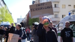 Демонстрант држи транспарент на кој пишува „Вакцинa тероризам“ за време на демонстрација на теоретичари на заговор, во Берлин, Германија, 18 април 202 година