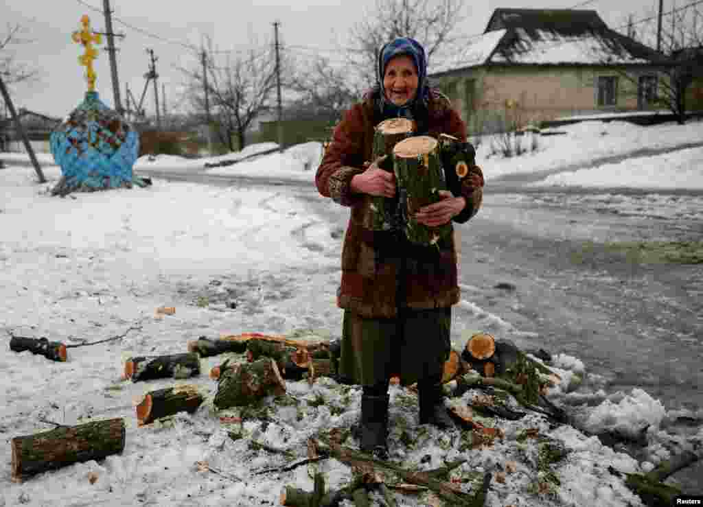 An elderly Ukrainian woman carries firewood for heating her home in the government-held industrial town of Avdiyivka in the war-torn Donbas region. (Reuters/Gleb Garanich)