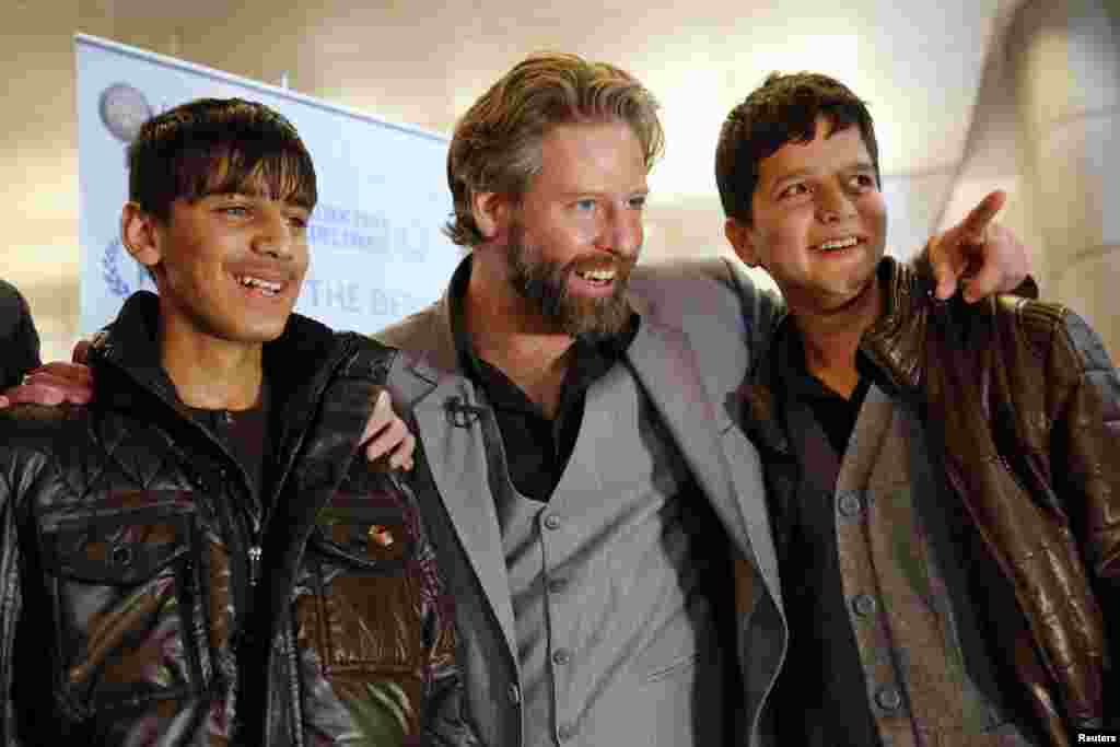 Director Sam French (center) and 14-year-old Afghan actors Fawad Mohammadi (left) and Jawanmard Paiz of the Oscar-nominated live-action short film &quot;Buzkashi Boys&quot; smile for the cameras after arriving at Los Angeles International Airport. (Reuters/Patrick Fallon)
