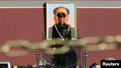 Пекиндегі Тяньаньмэнь алаңындағы Қытайдың бұрынғы басшысы Мао Цзэдунның үлкен суреті қасында тұрған қытай сарбазы. 12 қараша 2013 жыл. (Көрнекі сурет)