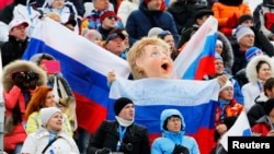 Fans hold Russian flags as they watch a skiing competition at the 2014 Winter Olympics in Sochi, Russia.