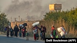 Syria -- Civilians flee with their belongings during Turkish bombardment on Syria's northeastern town of Ras al-Ain in the Hasakeh province along the Turkish border