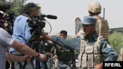 Afghan police keep journalists away from the site of a suicide car bomb attack in Kabul on August 18.