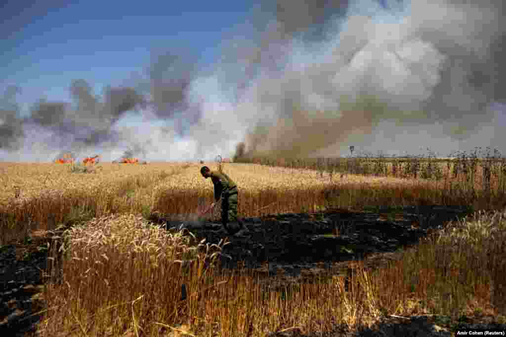 Ізраільскі салдат спрабуе патушыць пажар на ізраільскай баку мяжы паміж Ізраілем і паласой Газы 14 траўня.&nbsp;