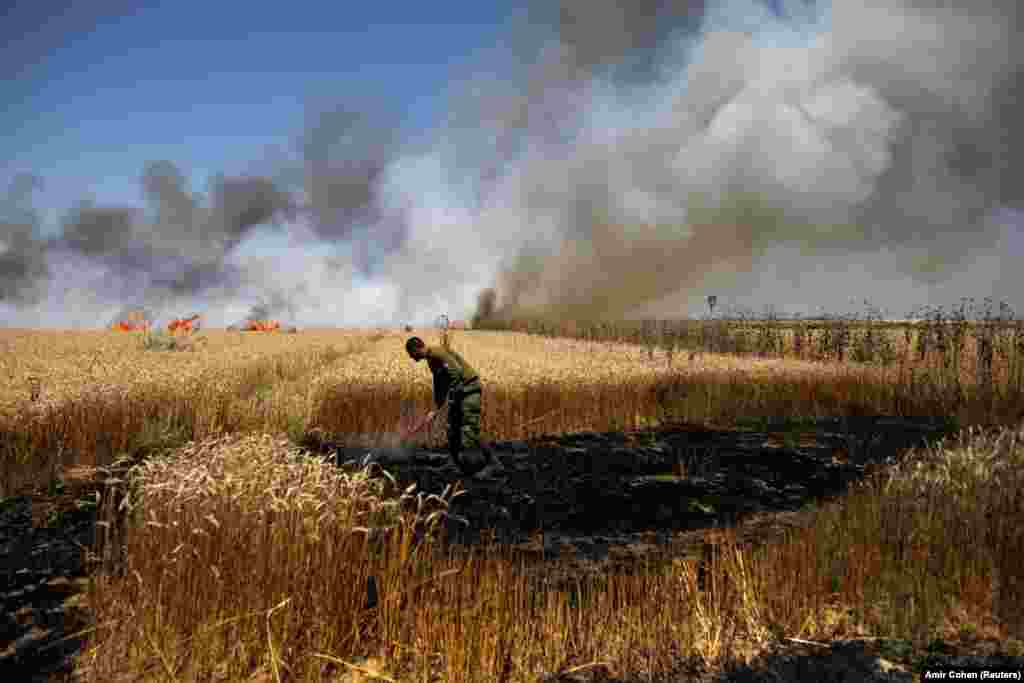 An Israeli soldier attempts to extinguish a fire in a field on the Israeli side of the border fence between Israel and Gaza on May 14. (Reuters/Amir Cohen)