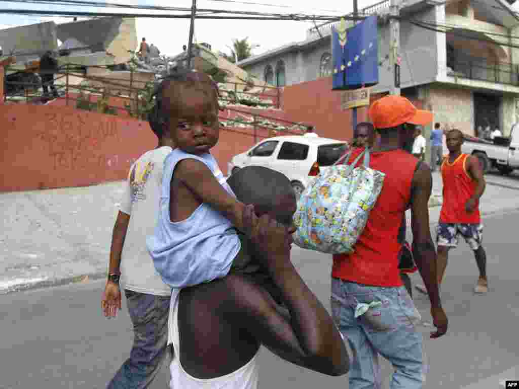 Людзі на вуліцы зьнішчанай землятрусам у сталіцы Гаіці, Порт-о-Прэнс.