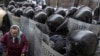 A elderly Ukrainian woman passes by security personnel as they cordon off pro-EU demonstrators near the Ministry of Internal Affairs in Kyiv on December 20. (Reuters/Gleb Garanich)