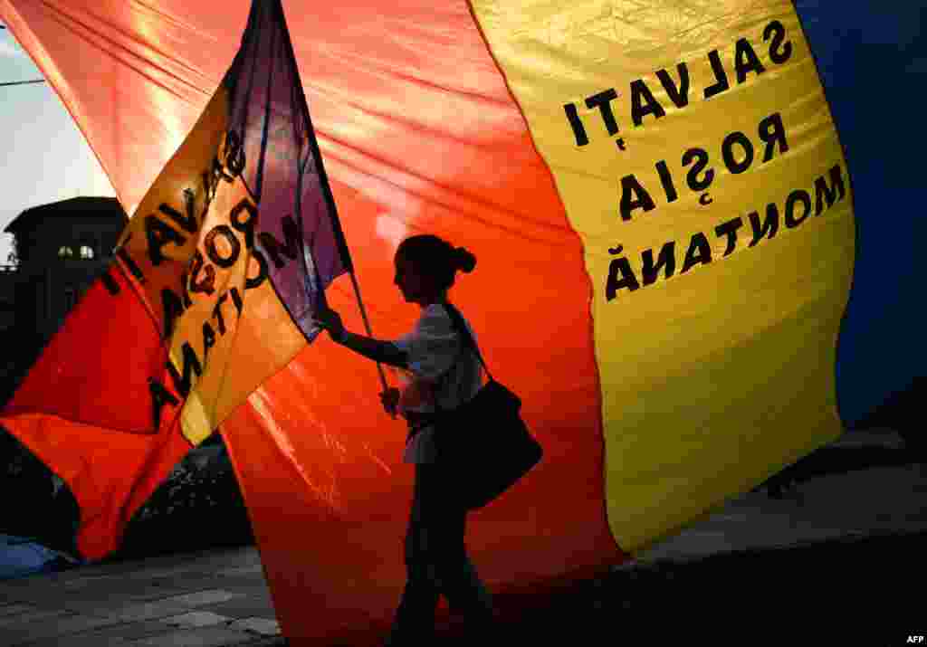 In Romania, a protester holds a flag reading &quot;Save Rosia Montana&quot; during a demonstration in Bucharest against a proposed open-cast gold mine. (AFP/Daniel Mihailescu)