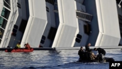 Rescuers pass in a small boat near the stricken cruise liner "Costa Concordia" lying aground in front of Giglio Island off the coast of Italy.