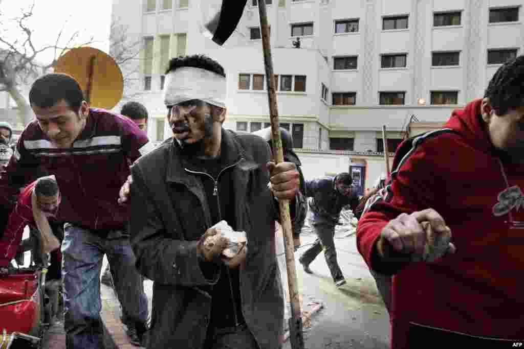 Egyptian protesters run for cover as police open fire on crowds in central Cairo on January 29, 2011.