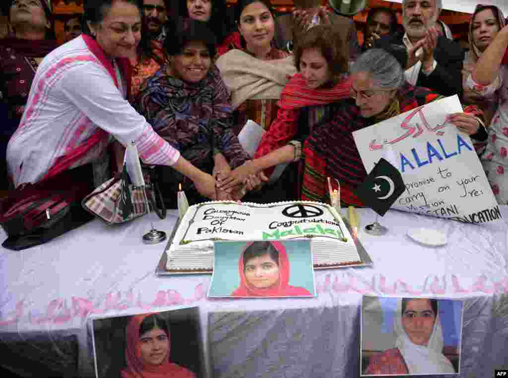 Pakistani activists pose for a photograph as they cut a cake in celebration of Yousafzai winning the Nobel Prize in Islamabad on October 14, 2014.