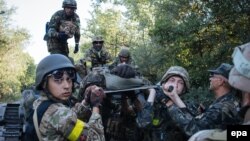 Українські військові несуть пораненого під час бою поблизу міста Іловайська, 10 серпня 2014 року 