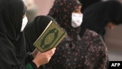 Saudi Arabia -- Women Muslim pilgrims wearing flu masks pray and read the Koran in the courtyard of the Prophet Mohammed Mosque in Medina, 12Nov2009