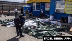 Ukrajinski policajac nad tijelima civila ubijenih u ruskom raketnom napadu na željezničku stanicu u Kramatorsku u aprilu 2022.