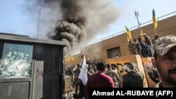 Suporterii milițiilor irakiene după ce au doborât o poartă la complexul de clădiri al ambasadei americane din Irak, 31 decembrie 2019