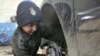 A 12-year-old boy works in a garage in Baghdad.