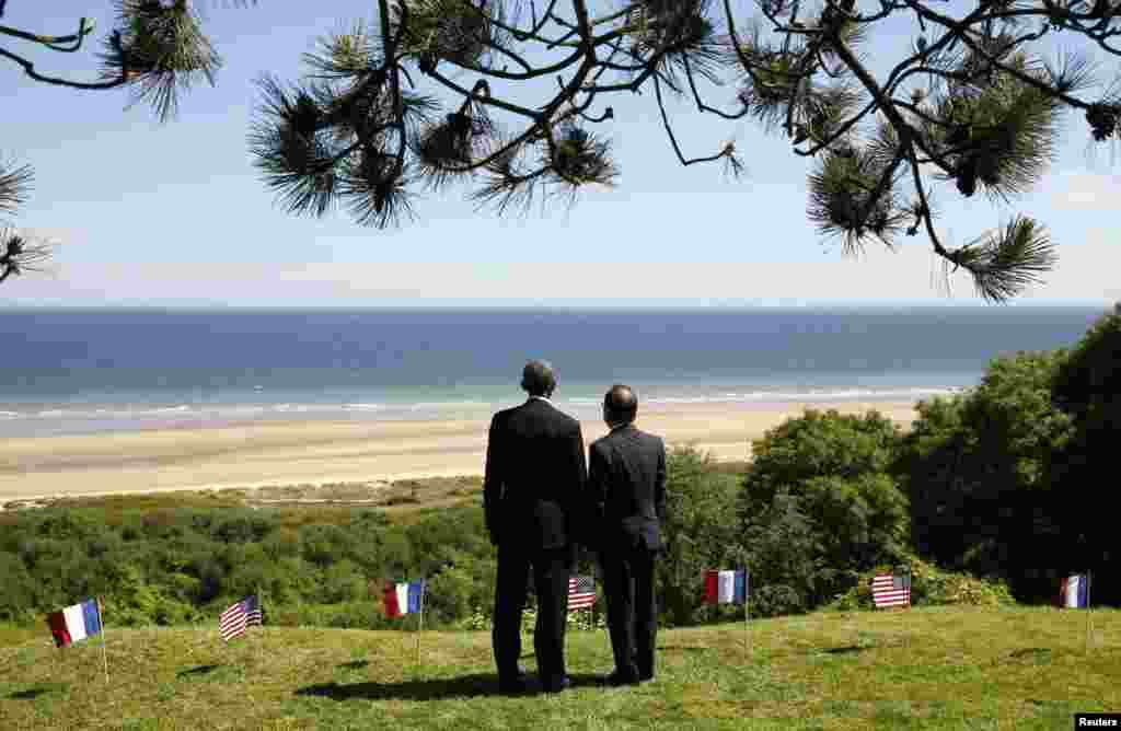 U.S. President Barack Obama and French President Francois Hollande look out over Omaha Beach as they participate in the 70th French-American Commemoration D-Day Ceremony at the Normandy American Cemetery and Memorial in Colleville-sur-Mer.