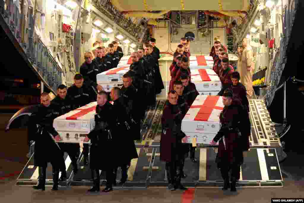 Georgian honor guards carry the coffins of soldiers killed in Afghanistan at an airport near the capital, Tbilisi, on June 9.