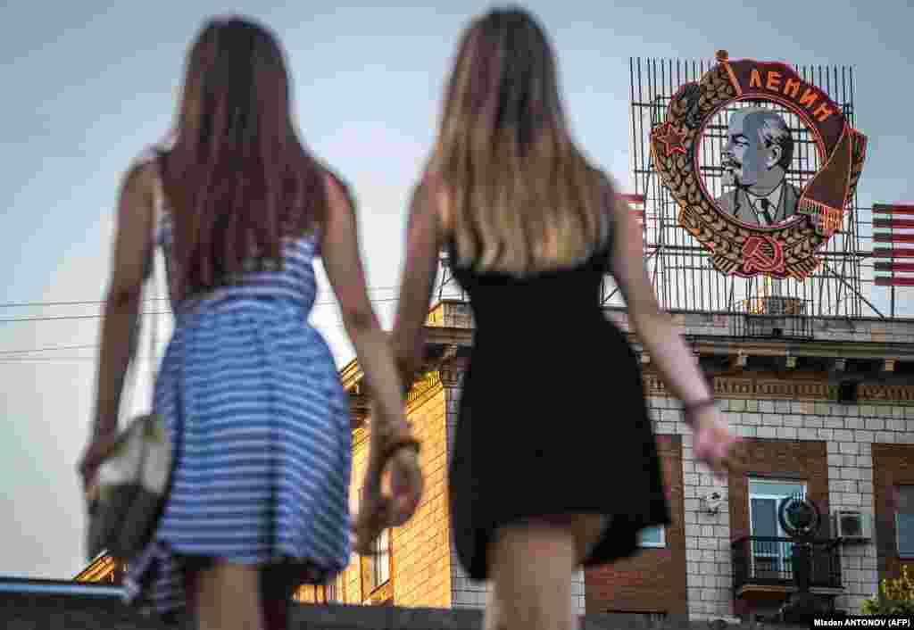 Russian girls pass in front of a building with a display of Soviet state founder Vladimir Lenin Order in Volgograd (formerly Stalingrad). (AFP/Mladen Antonov)