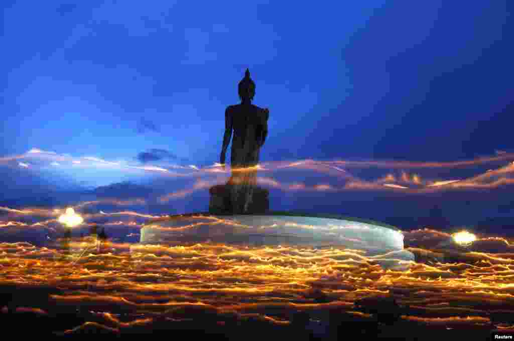 Thai Buddhists carry candles while encircling a large Buddha statue during Vesak Day, an annual celebration of Buddha&#39;s birth, enlightenment and death, at a temple in Nakhon Pathom Province on May 24. (Reuters/Chaiwat Subprasom)