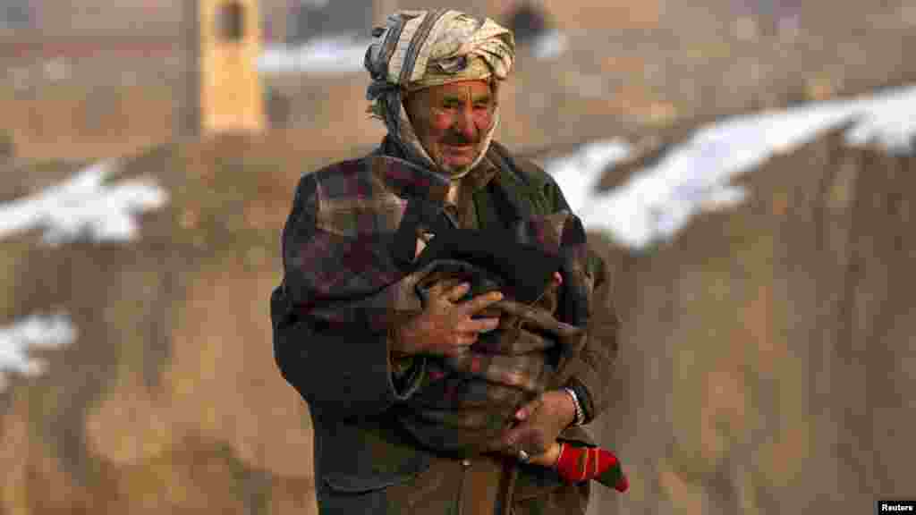 A man protects his child from the cold on a road in Kabul, Afghanistan. (Photo by Ahmad Masood for Reuters)