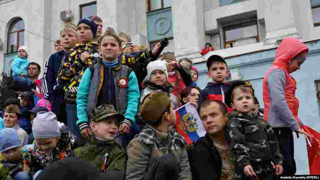9 мая 2019, Симферополь. Дети наблюдают за парадом военной техники в центре города. Для лучшей видимости они взобрались на выставленный у здания крымского правительства бронетранспортер