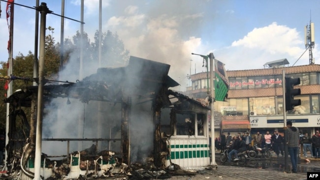 Iranians gather around a charred police station that was set ablaze by protesters during a demonstration against a rise in gasoline prices in the central city of Isfahan, November 17, 2019