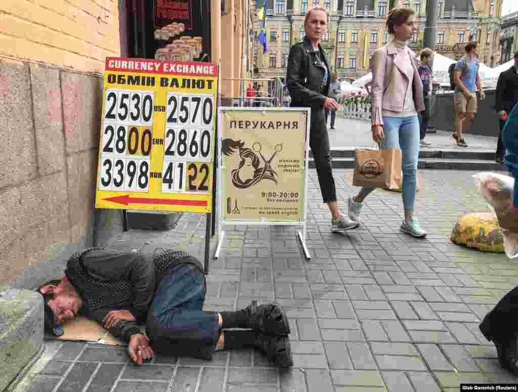 A man sleeps near a currency-exchange office&#39;s display board in central Kyiv on August 2 (Reuters/Gleb Garanich)