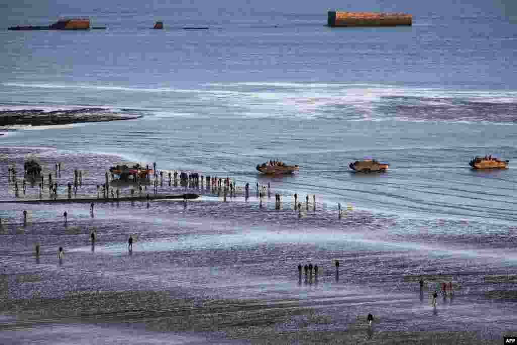 FRANCE -- WWII enthusiasts walk near DUKW (colloquially known as Duck), a six-wheel-drive amphibious modification of the 2 1/2-ton CCKW trucks used by the U.S. military, on the beach of Asnelles, in Normandy, on June 6, 2019