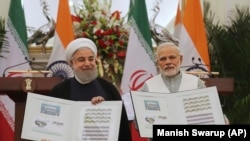 INDIA -- Indian Prime Minister Narendra Modi, right, with Iranian President Hassan Rohani release a postal stamp commemorating growing economic and trade ties between the two nations in New Delhi, February 17, 2018