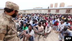 Pripadnik obezbeđenja nadgleda ljude iz podsaharske Afrike u pritvorskom centru u Tripoliju, Libija, 4. jun 2015.