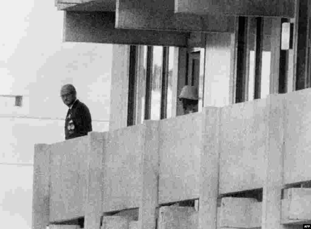 A Palestinian terrorist (right) appears on a balcony at the Israeli apartment watching an official at the Olympic village at the height of the crisis on September 5, 1972.
