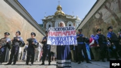 Фото пізнішого періоду. Українка тримає плакат з гаслом «Московський патріархат – це прокляття для України!» під час протесту перед кордоном міліції біля входу до Києво-Печерської лаври. Київ, 13 серпня 2014 року