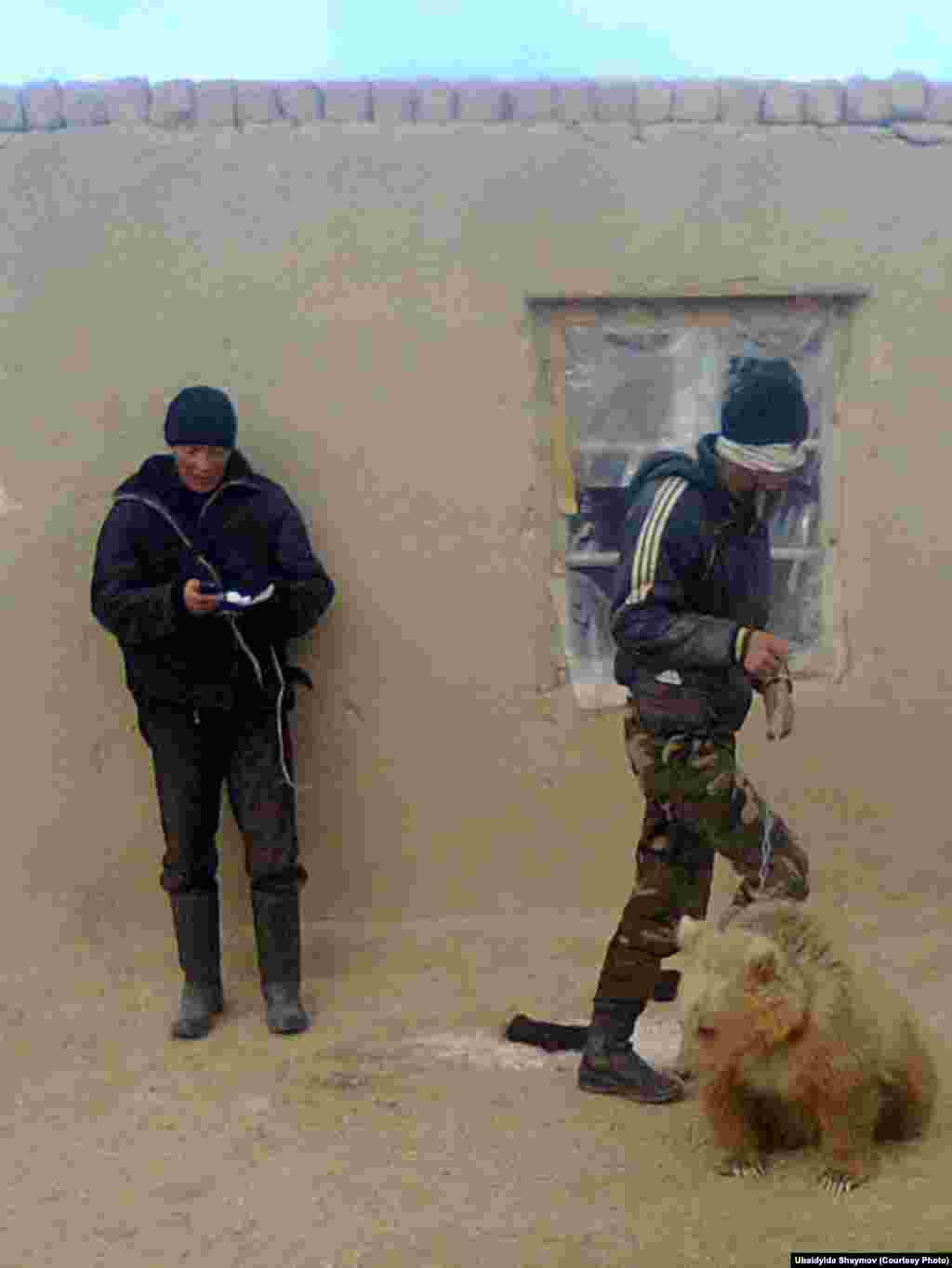 Misha the bear cub with two men from the village