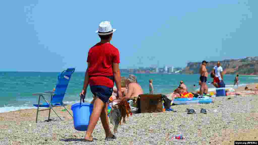 Школяр на канікулах продає відпочивальникам рибу на пляжі в селищі Любимівка, що на Північній стороні Севастополя