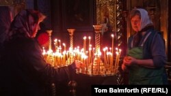 Two elderly women place prayer candles in Kyiv's St. Michael's monastery on Easter Sunday.