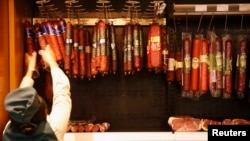 Сотрудница супермаркета в отделе колбасной продукции супермаркета. Иллюстративное фото.