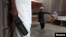 A security guard with a metal detector stands at the entrance of the shrine of Hasan-al-Maroof Sultan Manghopir, better known as the crocodile shrine, on the outskirts of Karachi on October 13.