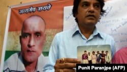 FILE: Indian friends of Kulbhushan Jadhav hold a photograph of them with Jadhav in the neighborhood where he grew up in Mumbai.