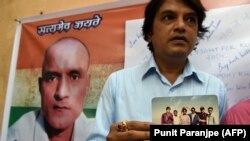 Friends of Kulbhushan Jadhav hold a photograph of them with Jadhav in the neighborhood where he grew up in Mumbai in May 18, 2017.